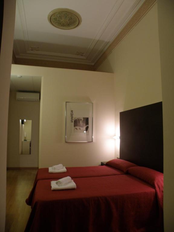 a bedroom with a red bed with two towels on it at Center Gran Via in Barcelona