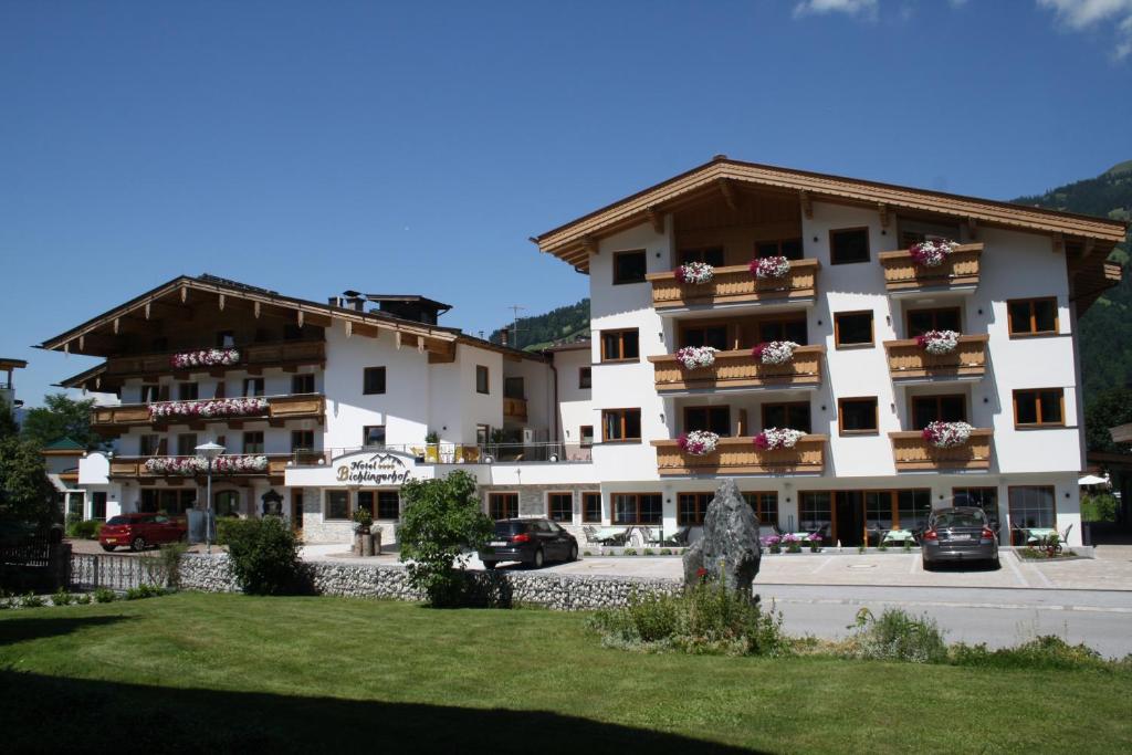 un gran edificio de apartamentos con coches aparcados frente a él en Hotel Bichlingerhof, en Westendorf