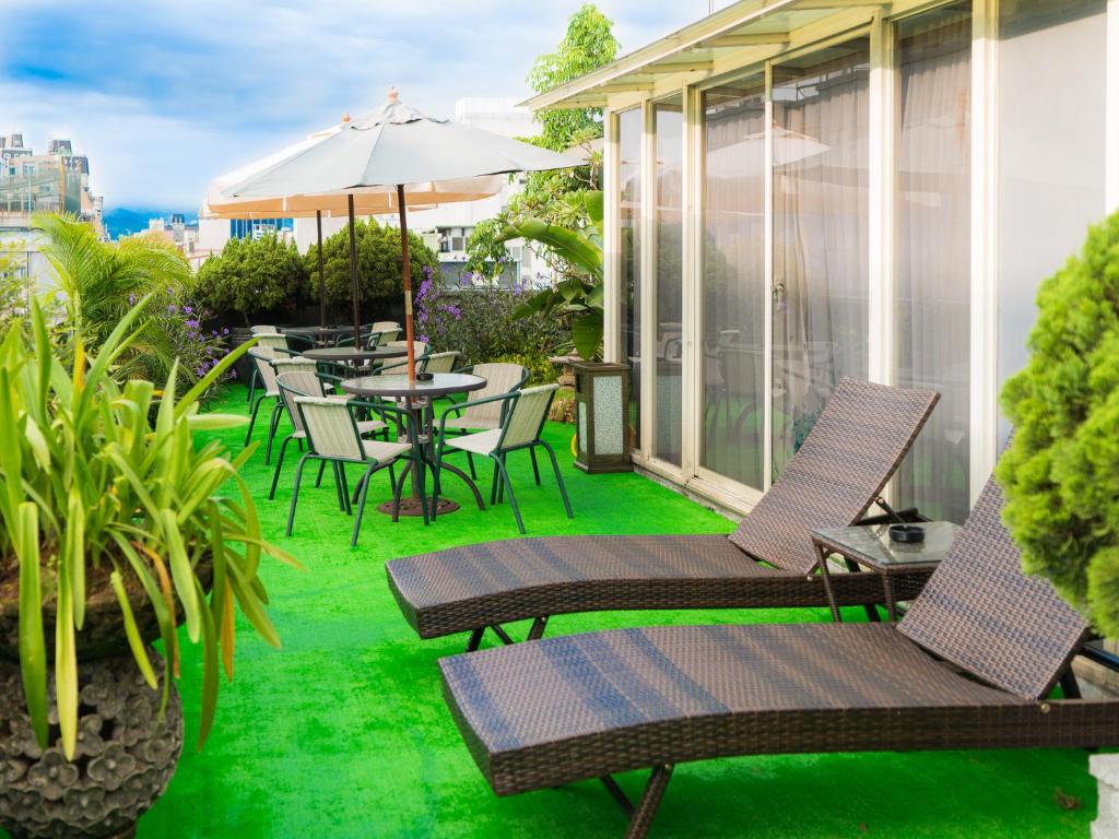 an outdoor patio with chairs and tables with green grass at E-House Hotel in Taipei
