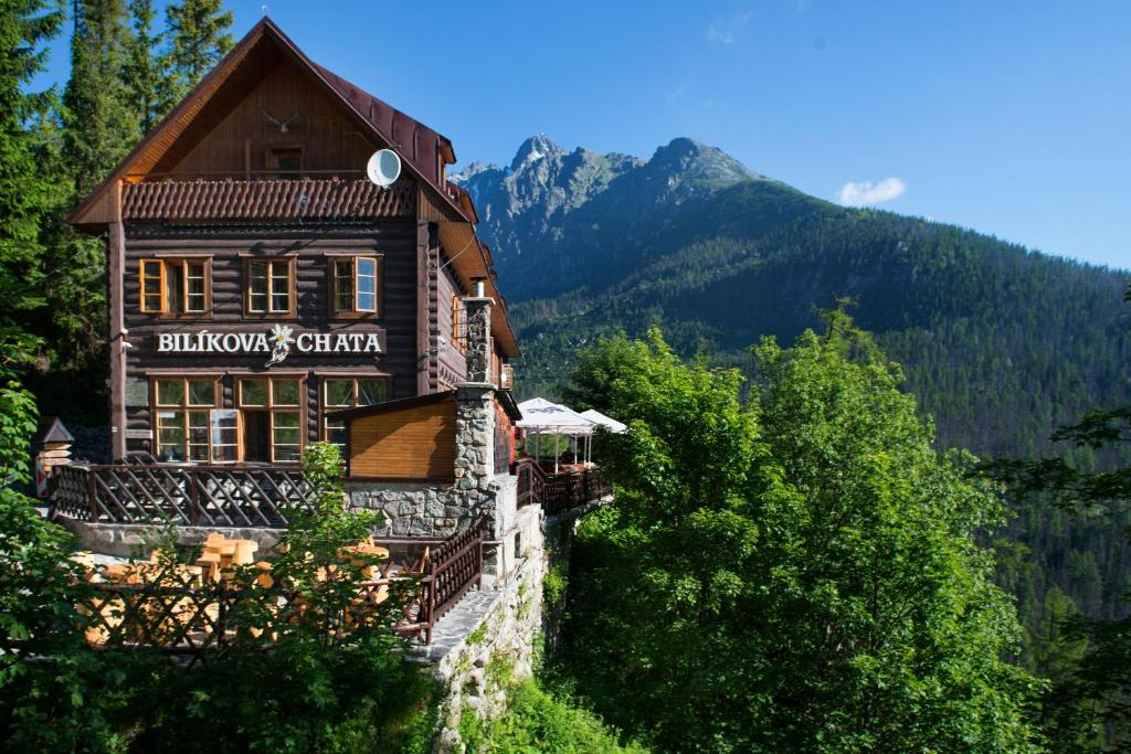 a building with a sign on the side of a mountain at BILÍKOVA CHATA - Horský hotel in Vysoke Tatry - Stary Smokovec