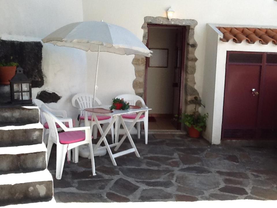 una mesa y sillas con una sombrilla en el patio en Casinha à beira ribeirio, en Manteigas