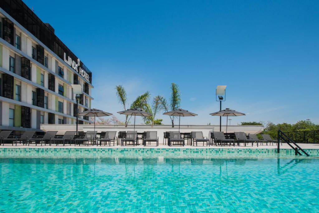 a swimming pool with chairs and umbrellas next to a building at Linx Galeão in Rio de Janeiro