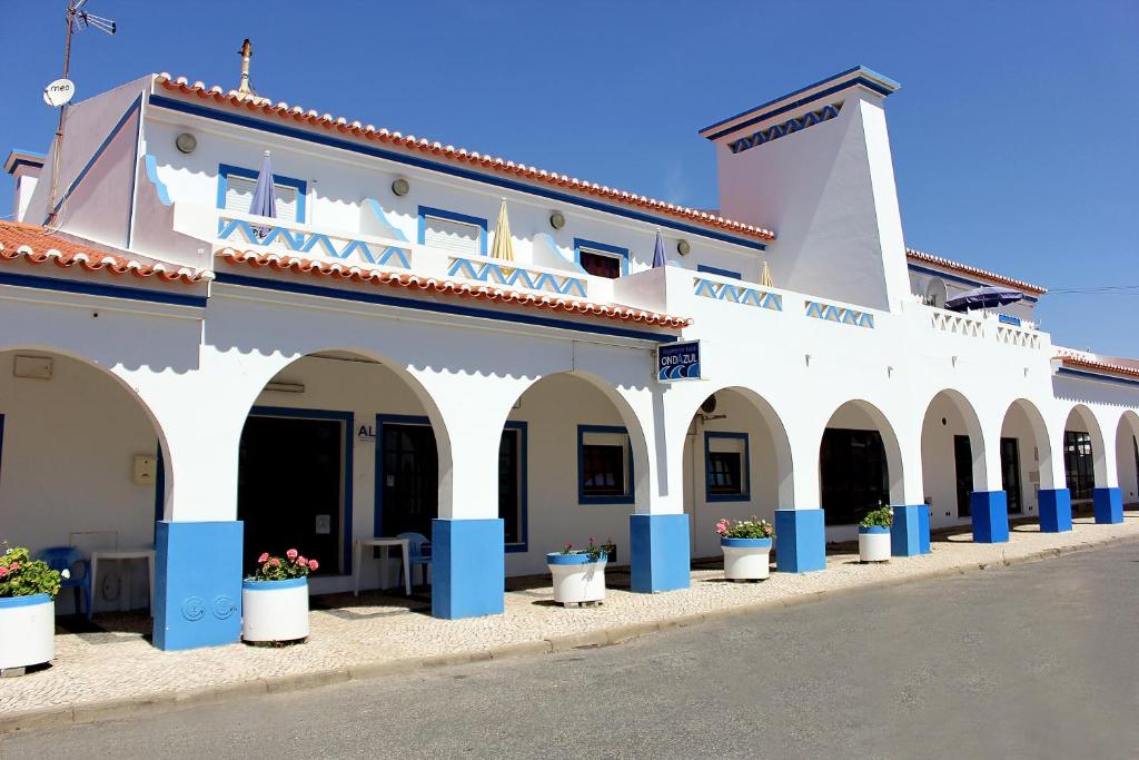 a large white building with arches on a street at Ondazul in Zambujeira do Mar