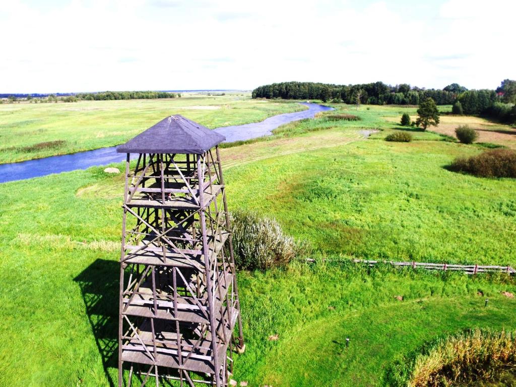 a wooden tower in a field next to a river at Wieża nad Biebrzą in Dolistowo