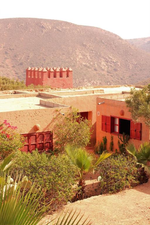 a house in the desert with a mountain in the background at Hotel De Charme Les 3 Chameaux 4 étoiles in Mirleft