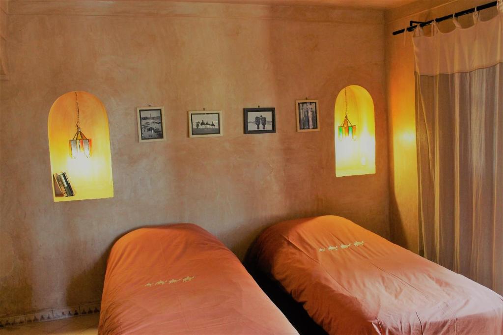 two beds in a room with pictures on the wall at Hotel De Charme Les 3 Chameaux 4 étoiles in Mirleft