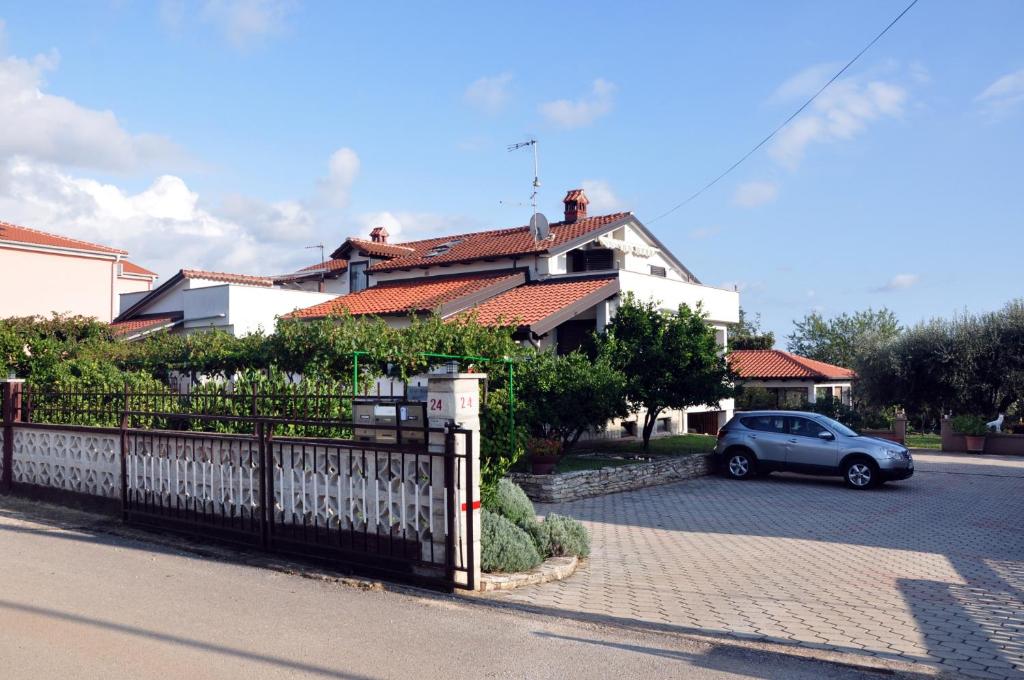 a car parked in front of a house with a fence at Franko Apartmani in Zambratija
