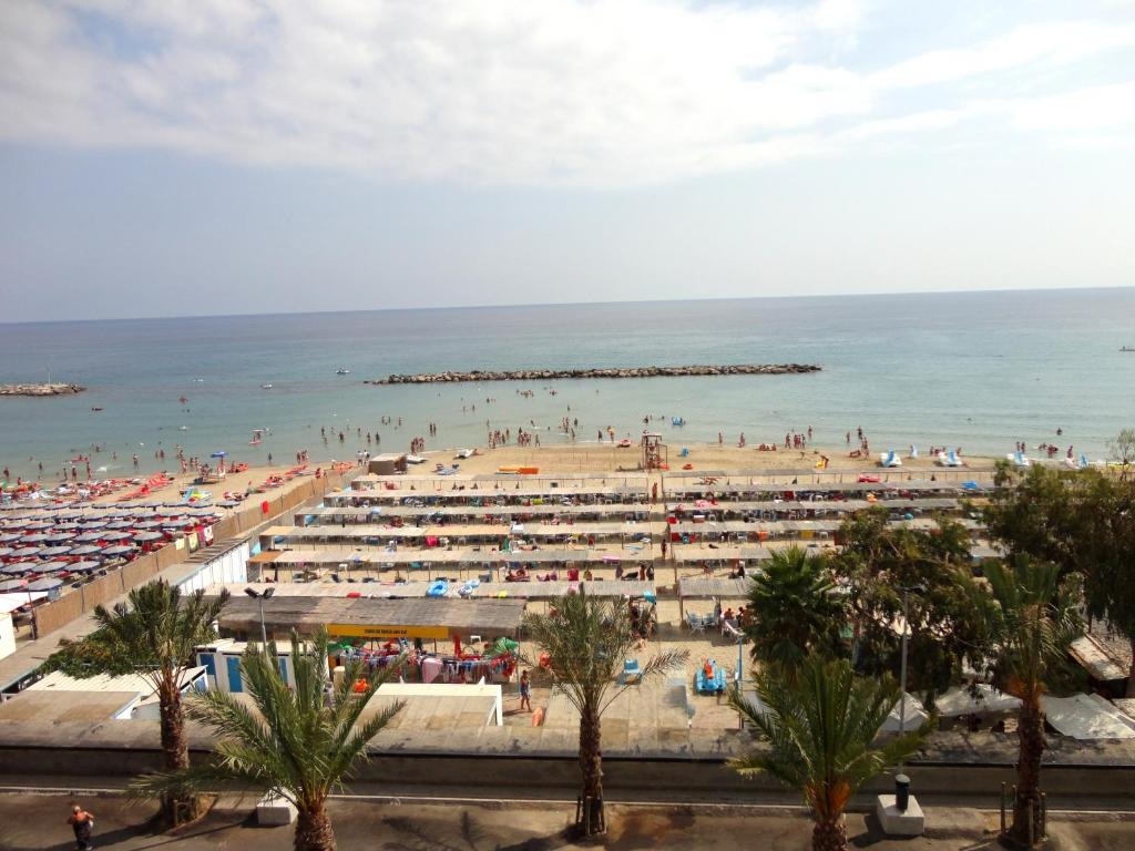 a beach with a lot of people and the ocean at Hotel Svizzera in Arma di Taggia