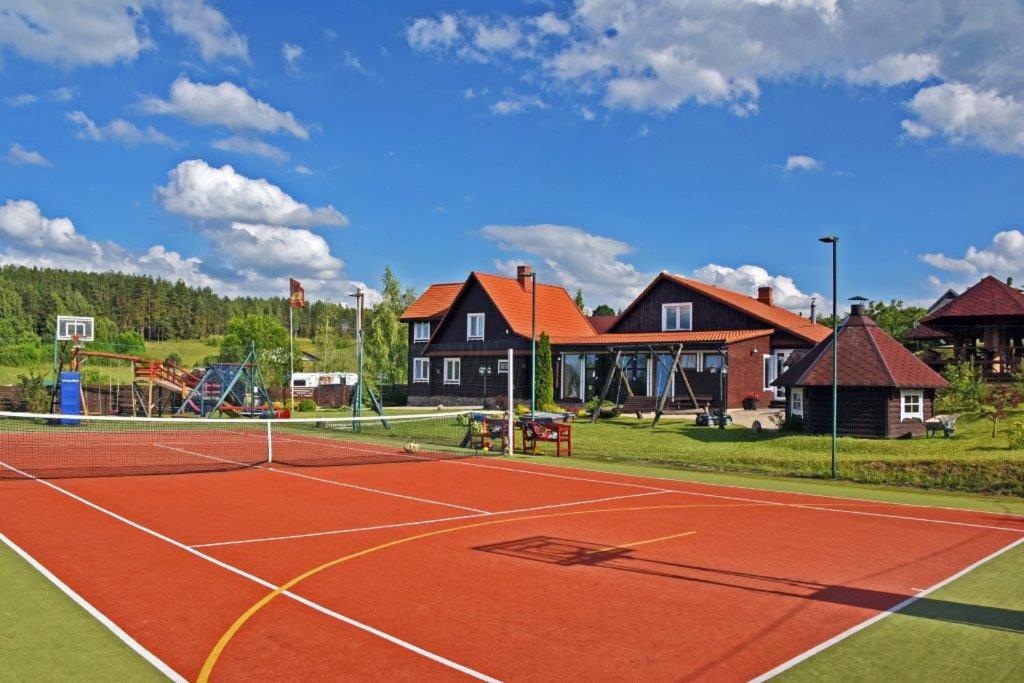 um campo de ténis com parque infantil e casas em Sodyba Sauletekis em Ignalina