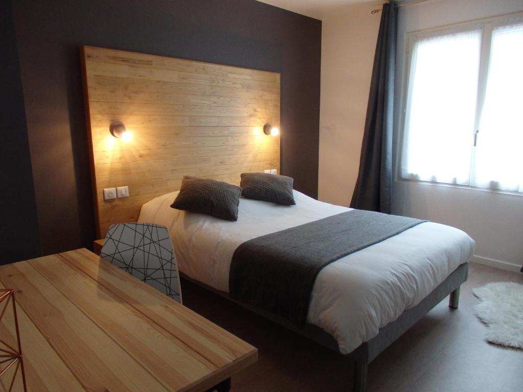 1 dormitorio con cama grande y cabecero de madera en Hotel Castel, en Neuves-Maisons