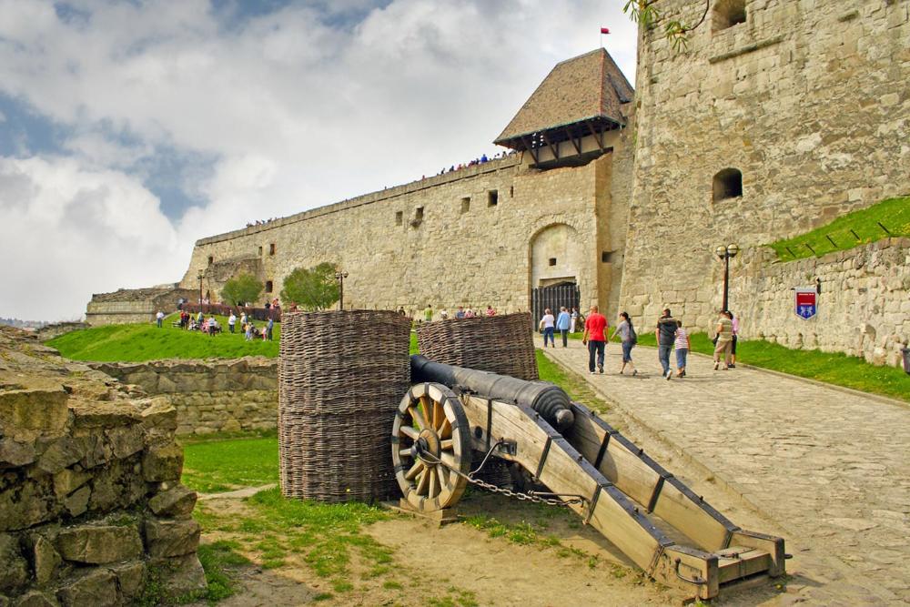 un canon assis à l'extérieur d'un château avec des gens se promener dans l'établissement Apartman Rosé, à Eger