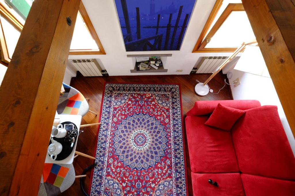 einen Blick über ein Wohnzimmer mit einer roten Couch und einem Teppich in der Unterkunft Mansardina San Marco in Venedig