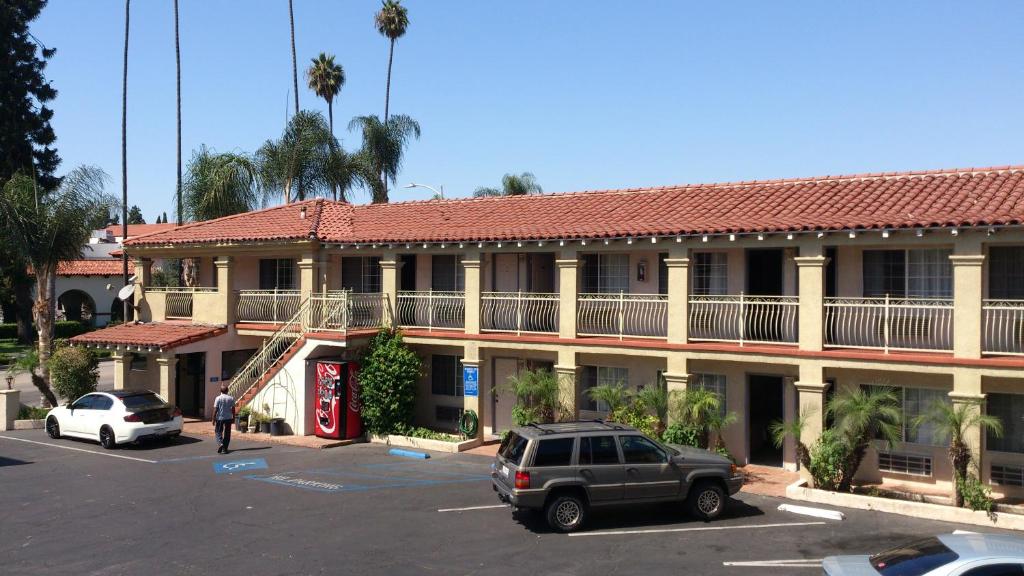 Santa Ana Travel Inn في سانتا آنا: مبنى كبير به سيارات تقف في موقف للسيارات