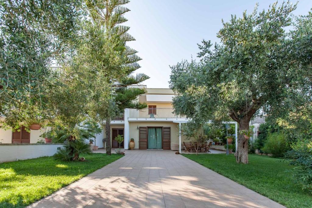 ein Haus mit Bäumen vor einer Einfahrt in der Unterkunft Giardino Dei Suoni B&B in Melendugno