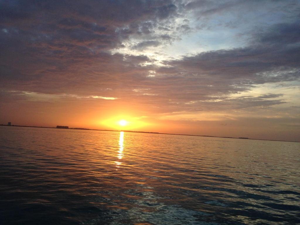 a sunset over a body of water with the sun setting at Los Caracoles Bed & Breakfast in Cancún