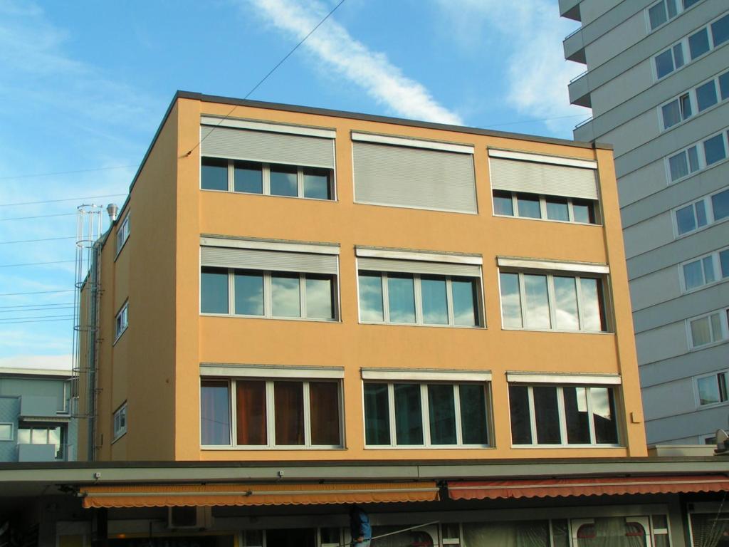 un edificio arancione con finestre accanto ad alcuni edifici di Swiss Star Oerlikon Station - Self Check-In a Zurigo