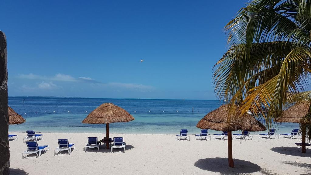 una playa con sillas y sombrillas y el océano en Departamento frente al Mar - Kiara en Cancún