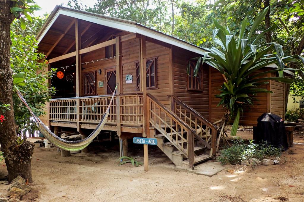 uma casa de madeira com uma rede em frente em Blue Island Divers Casita Azul em Sandy Bay