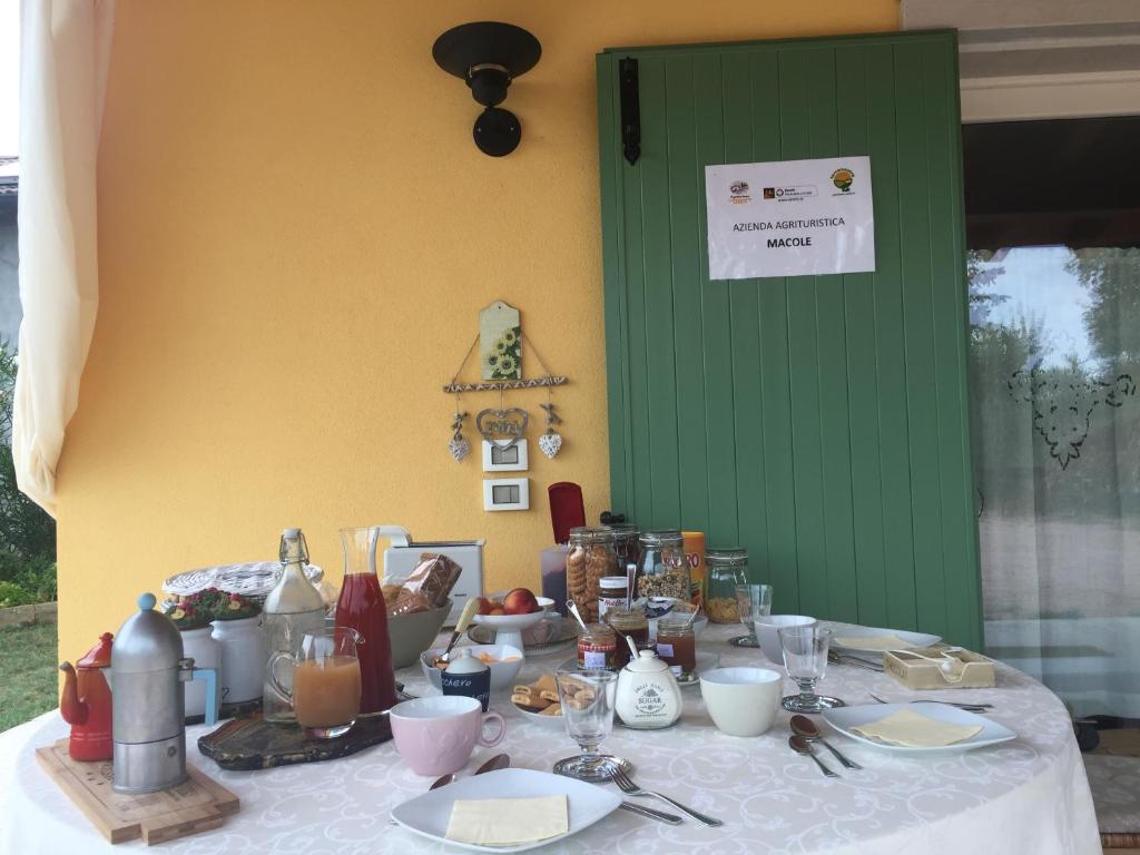 ヴェローナにあるAgriturismo MACOLE Fattoria con Spuntiniの白いテーブルクロスと食べ物