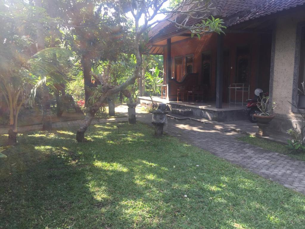 una casa con un patio con un árbol delante en Batan Duren House, en Ubud