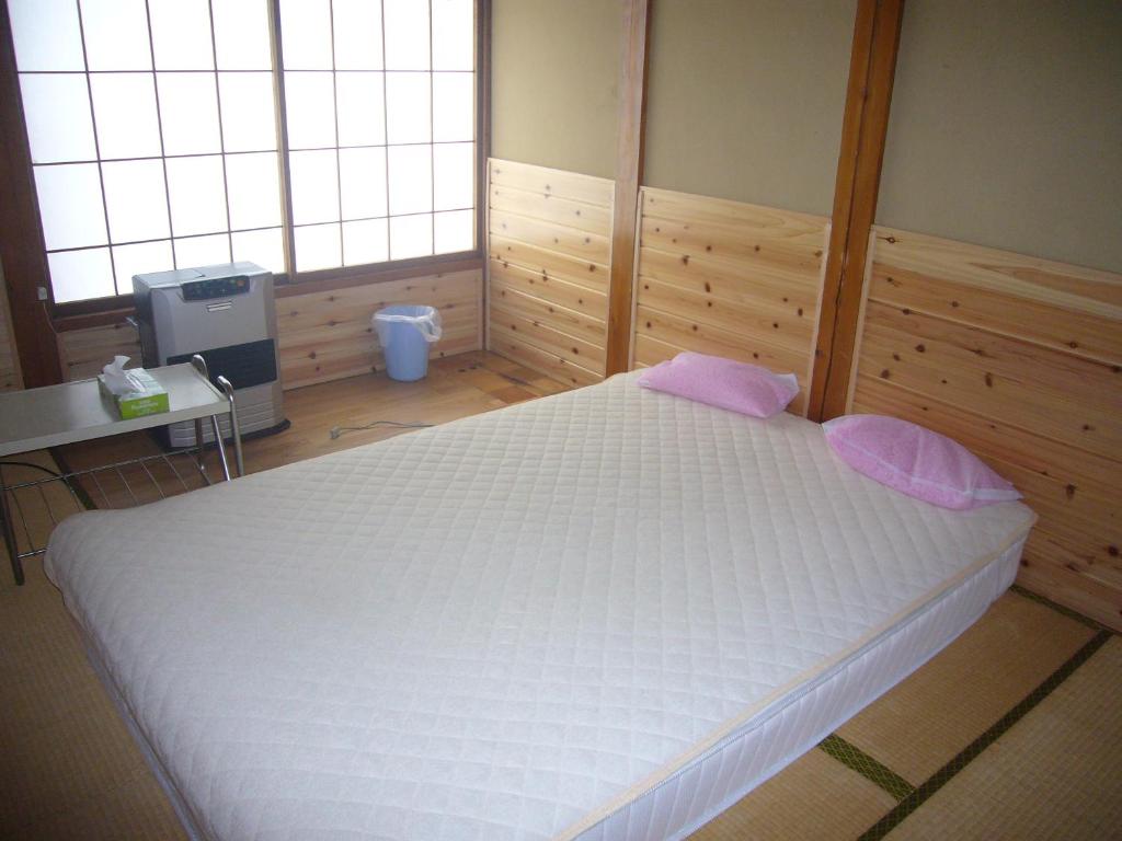 a large white bed in a room with two windows at Futago Cabin in Minami Uonuma