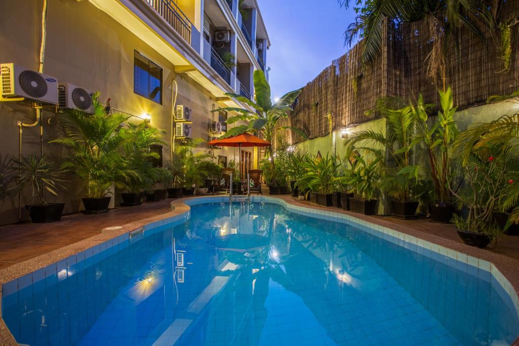 a swimming pool in front of a building with plants at La Villa du Bonheur in Siem Reap