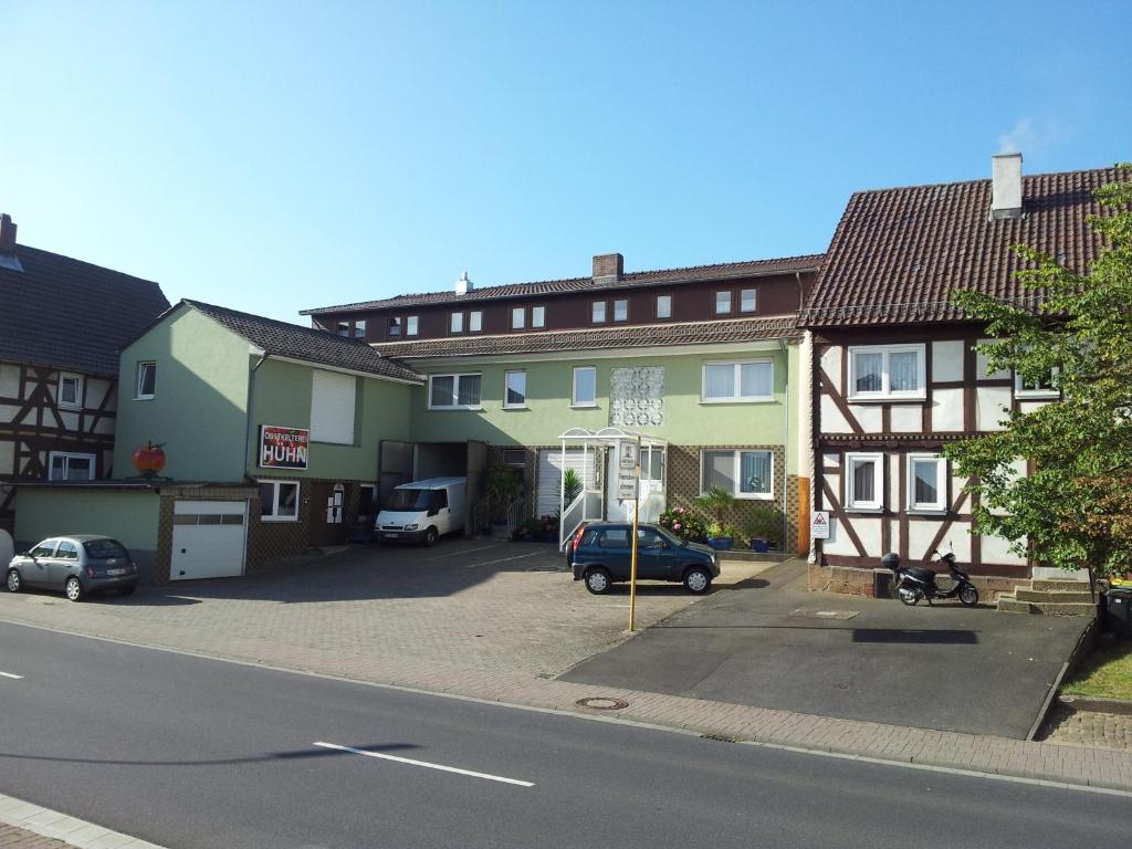 eine Gruppe von Gebäuden mit Autos auf einem Parkplatz in der Unterkunft Pension Hühn in Angersbach