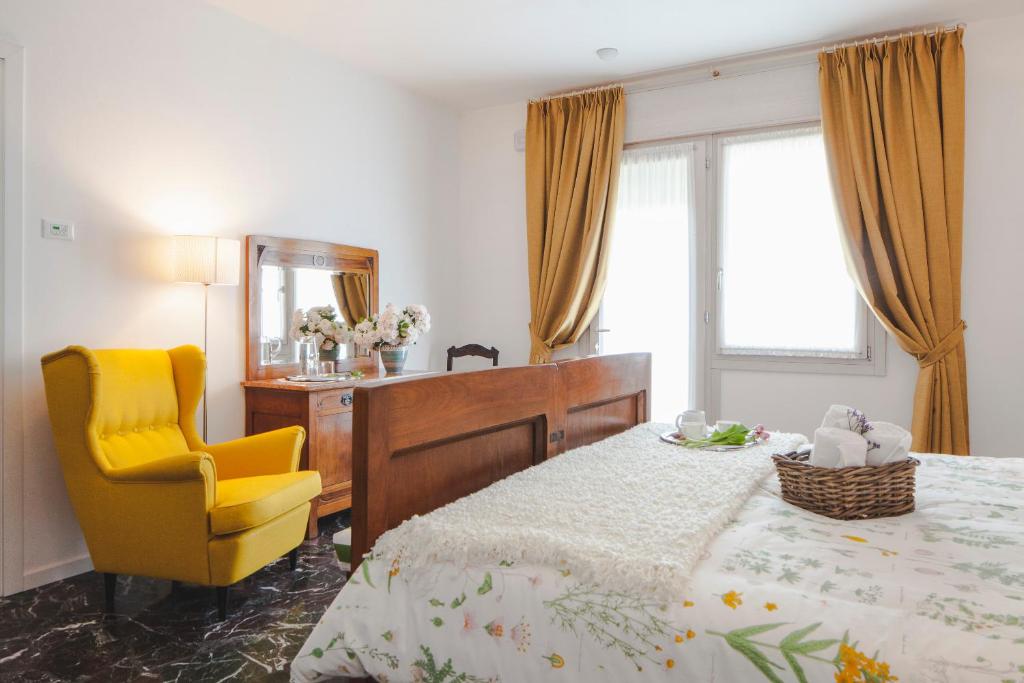 ein Schlafzimmer mit einem Bett, einem Stuhl und einem Spiegel in der Unterkunft Artemide Relais in Montebelluna
