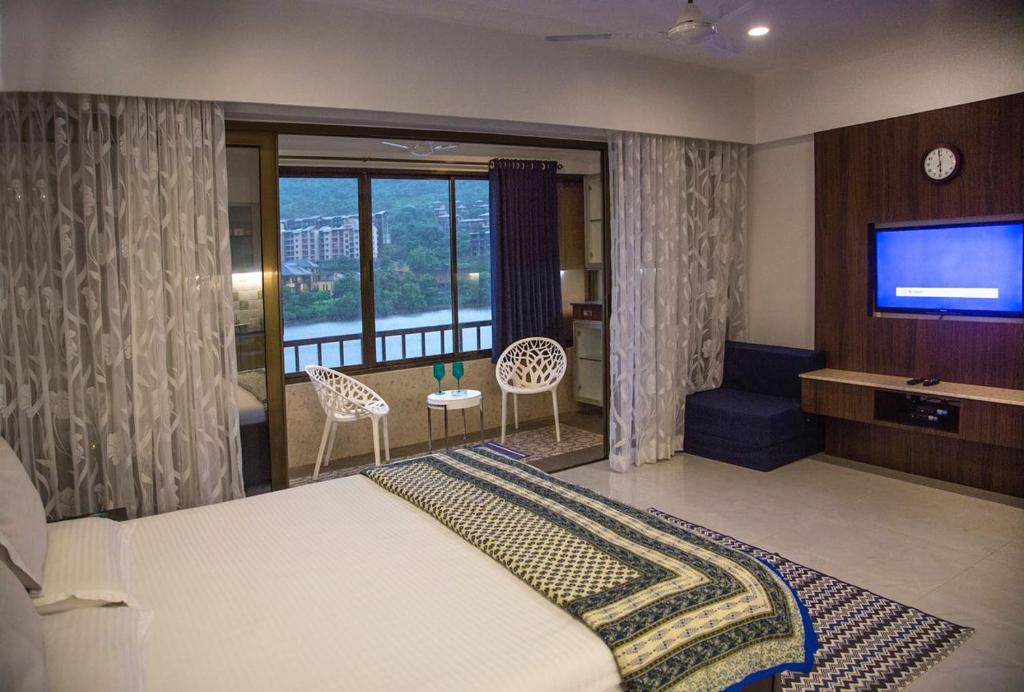 a bedroom with a bed and a flat screen tv at Lavasa Luxury Lakeview Studio in Lavasa