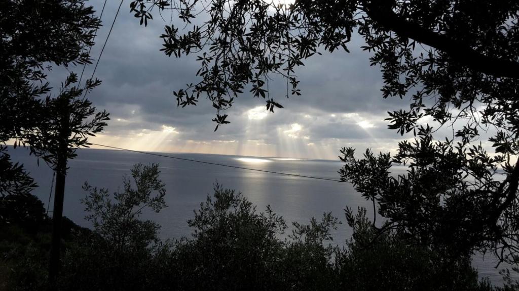 Corner of Paradise near Cinque Terre في فرامورا: اطلالة على المحيط مع اشعة الشمس من خلال السحب