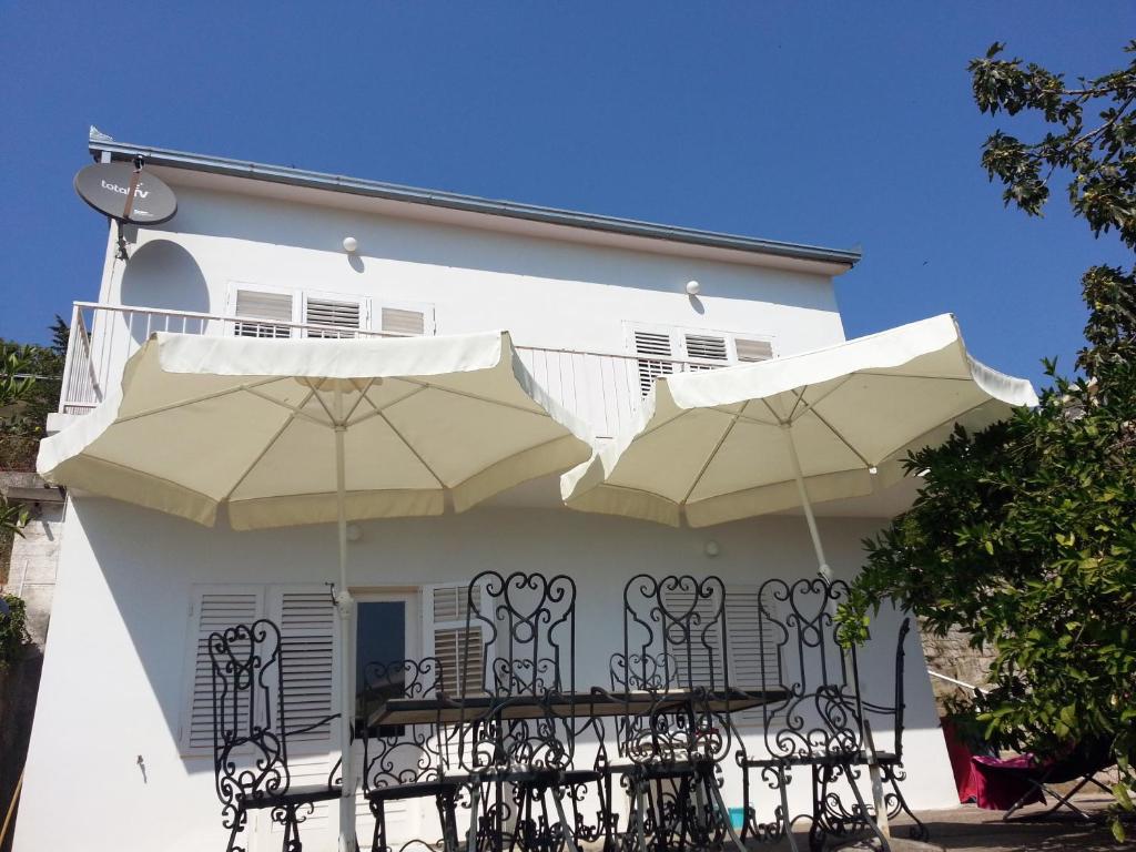 a white house with two umbrellas on a balcony at Villa Nostra - Kruče in Ulcinj