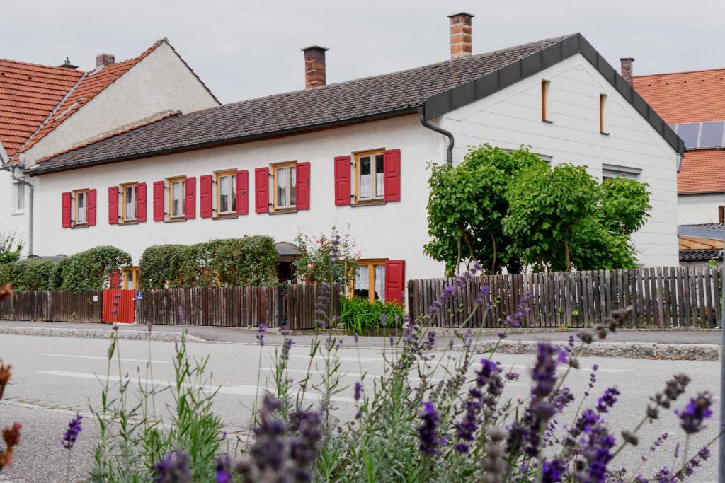 a white house with red shutters and purple flowers at ferienwohnung lispet in Neuötting