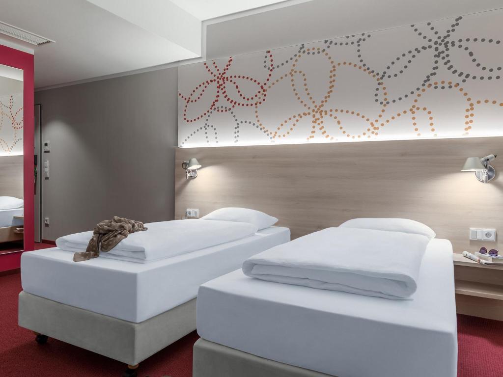 two white beds in a room with red carpet at Serways Hotel Siegburg West in Siegburg