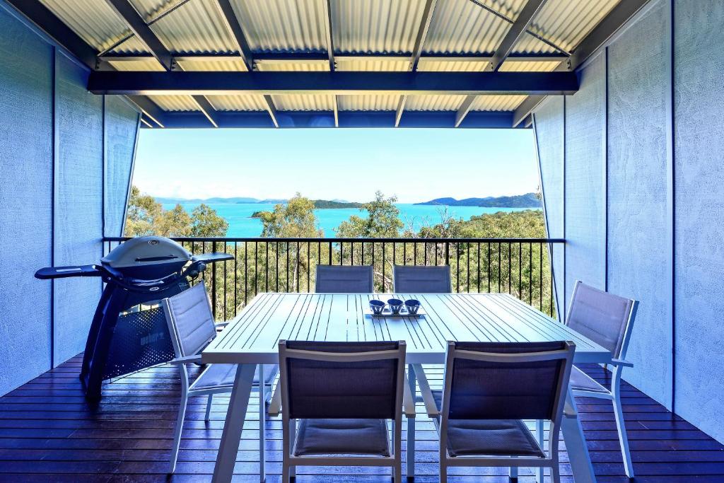 a table and chairs on a balcony with a grill at Panorama Apartments on Hamilton Island by HIHA in Hamilton Island