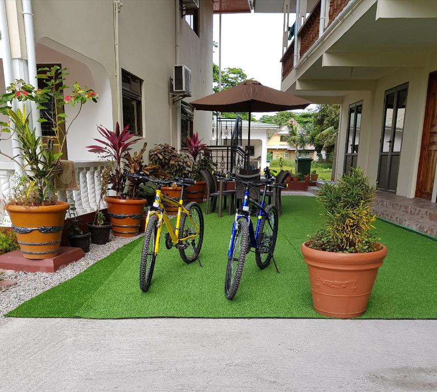 deux vélos garés sur un tapis vert devant une maison dans l'établissement Tourterelle Holiday Home, à Grand Anse