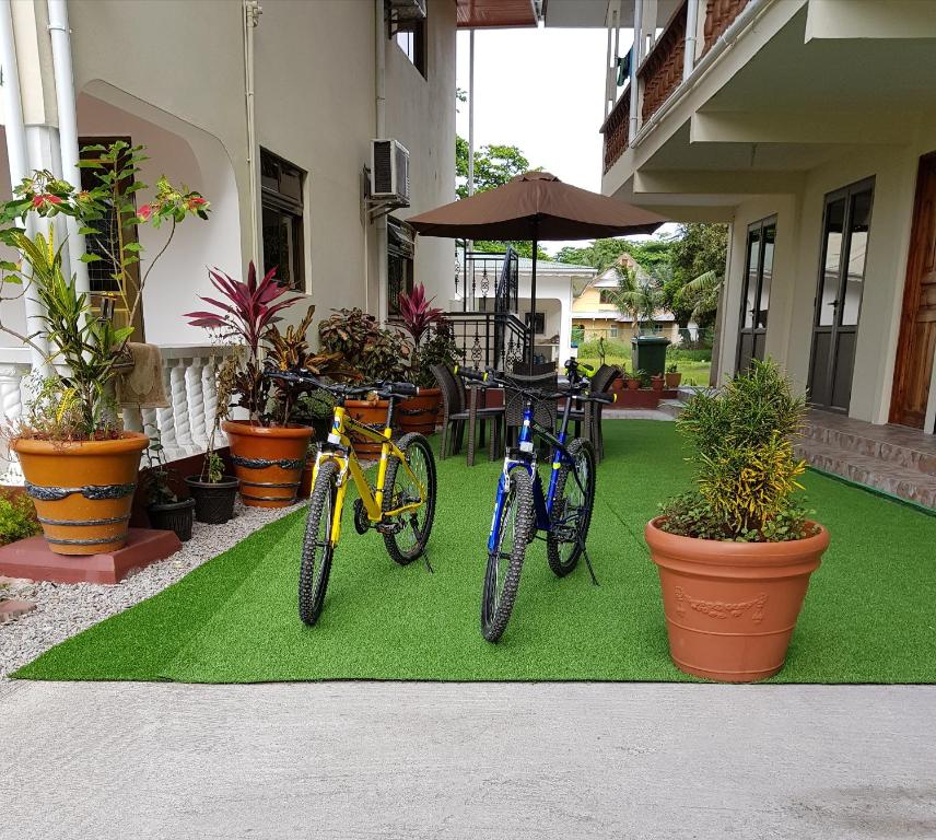 dos motos estacionadas en una alfombra verde frente a una casa en Tourterelle Holiday Home en Grand Anse