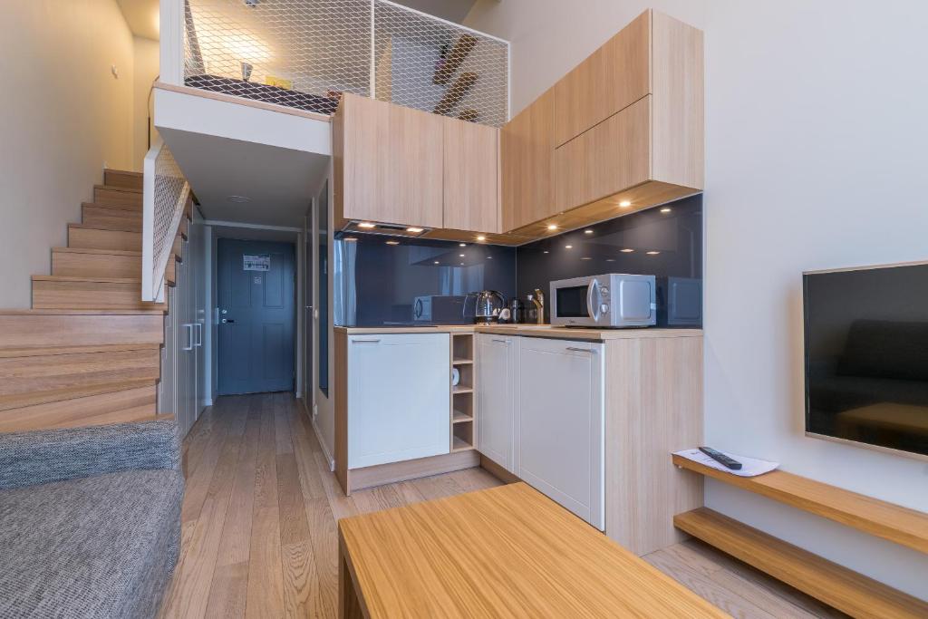 a living room with a kitchen and a staircase at Stay Apartments 14 in Tallinn