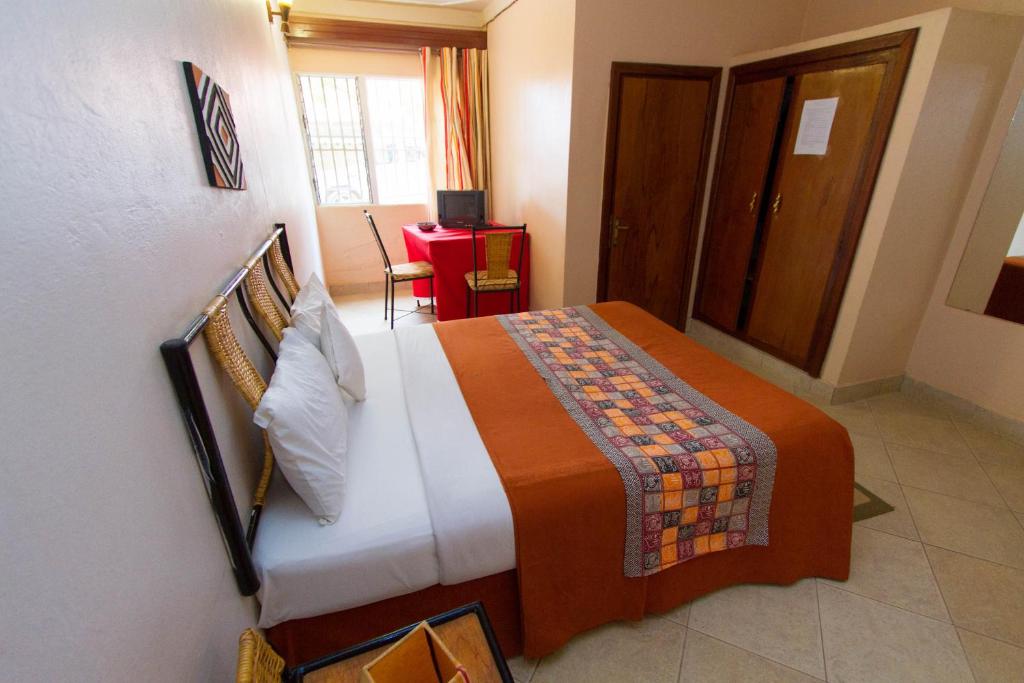 a bedroom with a bed with an orange blanket at Kings Hospitality Centre in Kigali