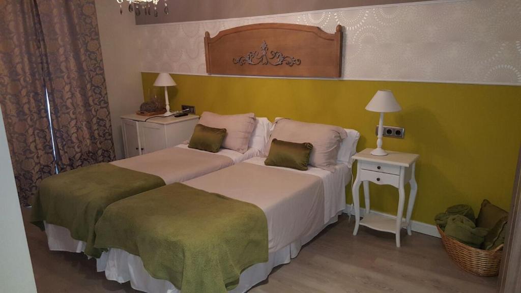 two beds in a room with green and white at El Encanto del Moncayo in Ágreda