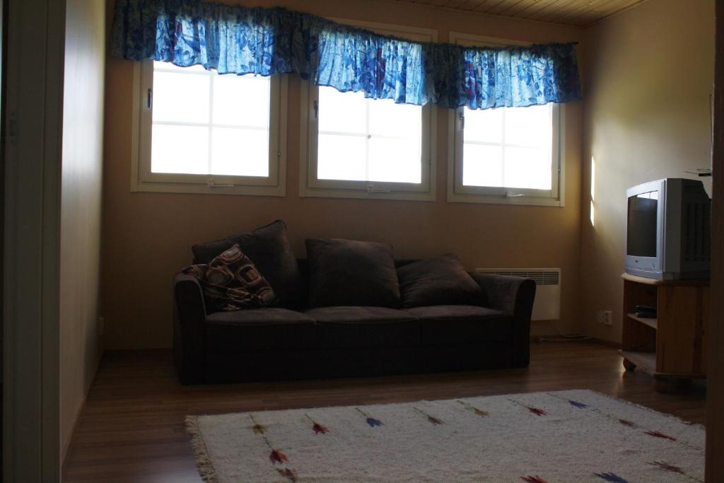 a living room with a couch and two windows at Surkeenjärven Jaakon talot in Moksinkylä