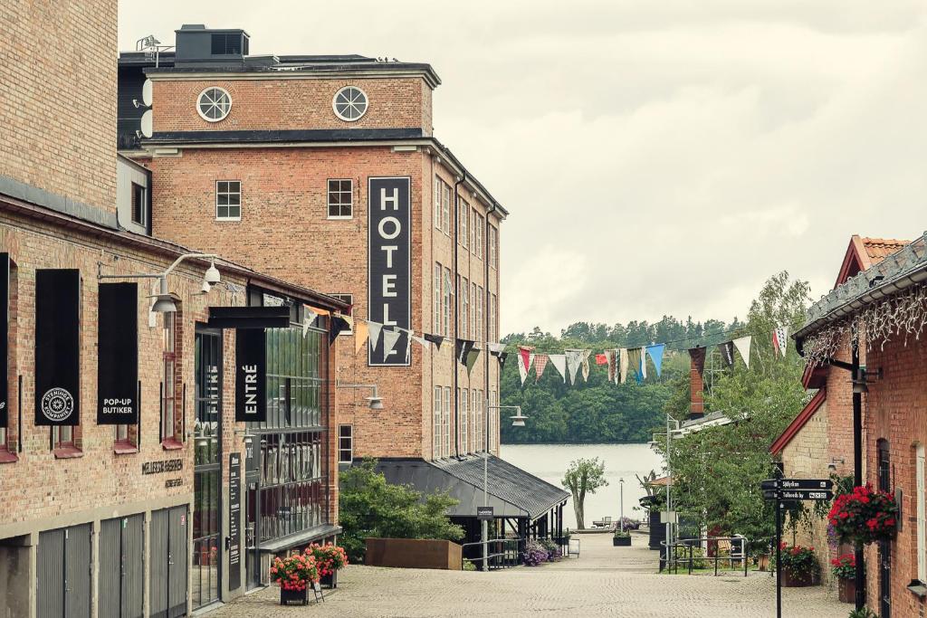 a brick building with a clock tower on a street at Nääs Fabriker Hotell & Restaurang in Tollered