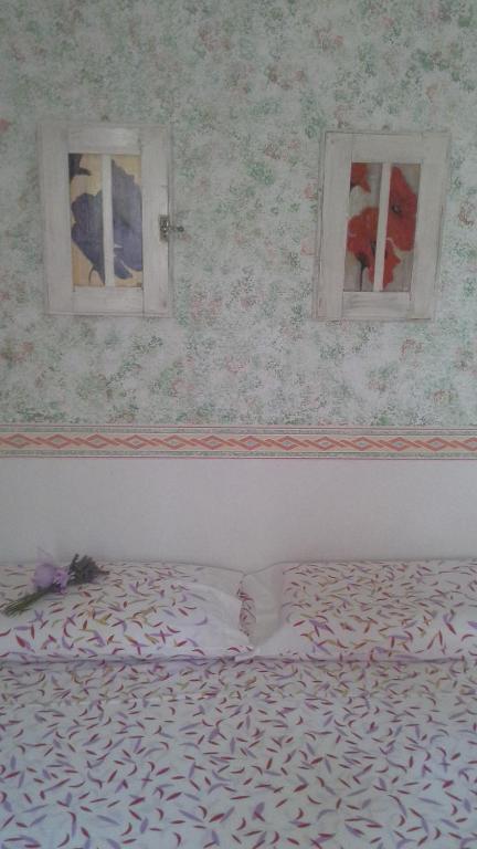 a bed in a room with two windows at Appartamento Casa dei Frati in Magliano in Toscana