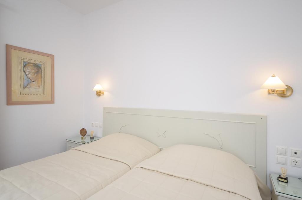 a white bed in a bedroom with two lamps at Astir Of Naxos in Naxos Chora