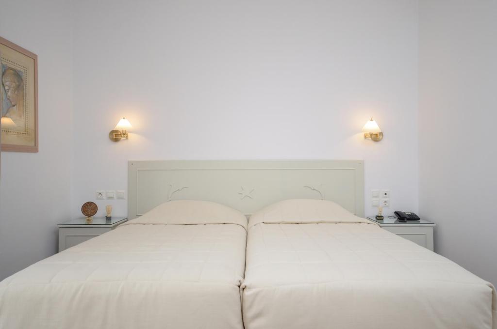 a white bed in a white bedroom with two lights at Astir Of Naxos in Naxos Chora