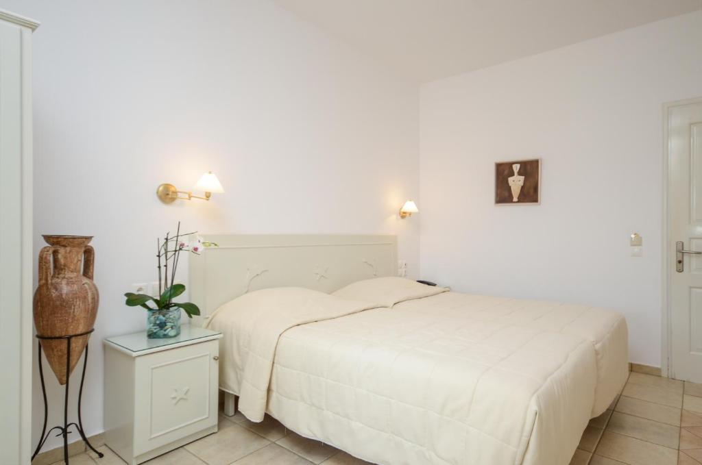 a white bedroom with a bed and a night stand at Astir Of Naxos in Naxos Chora