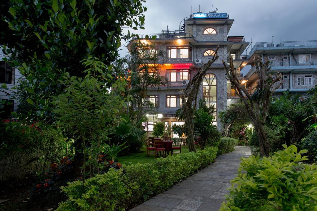budynek z wieżą zegarową na środku ogrodu w obiekcie Hotel Tulsi w mieście Pokhara