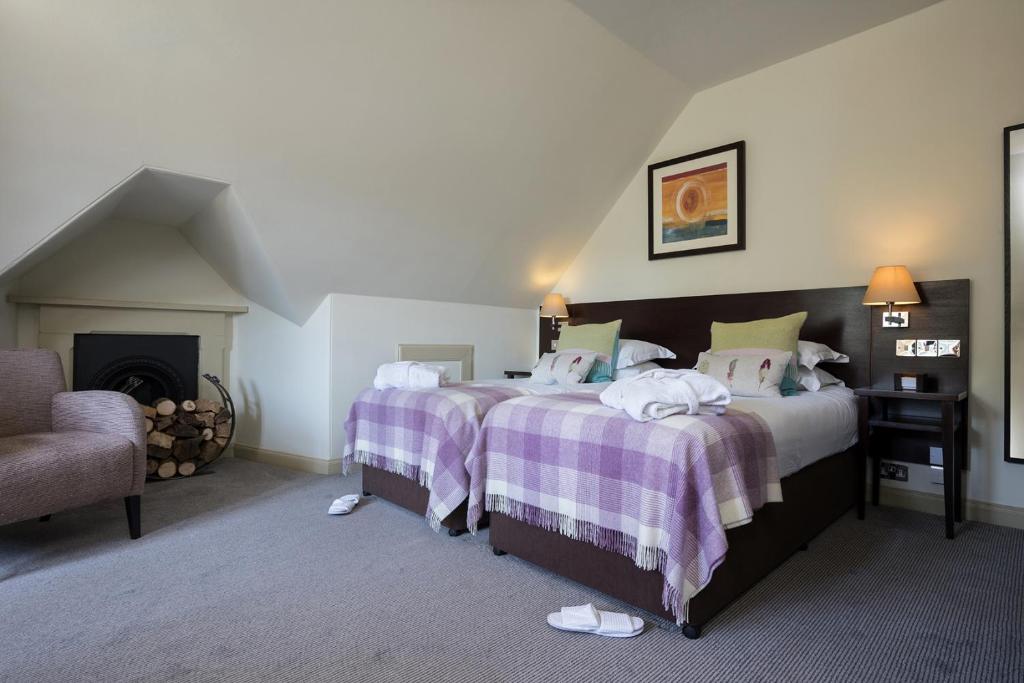 a bedroom with two beds and a fireplace at Nether Abbey Hotel in North Berwick