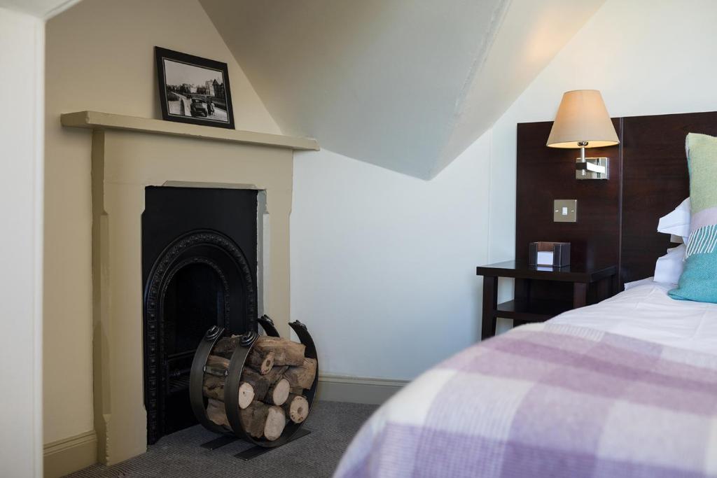 a bedroom with a fireplace next to a bed at Nether Abbey Hotel in North Berwick