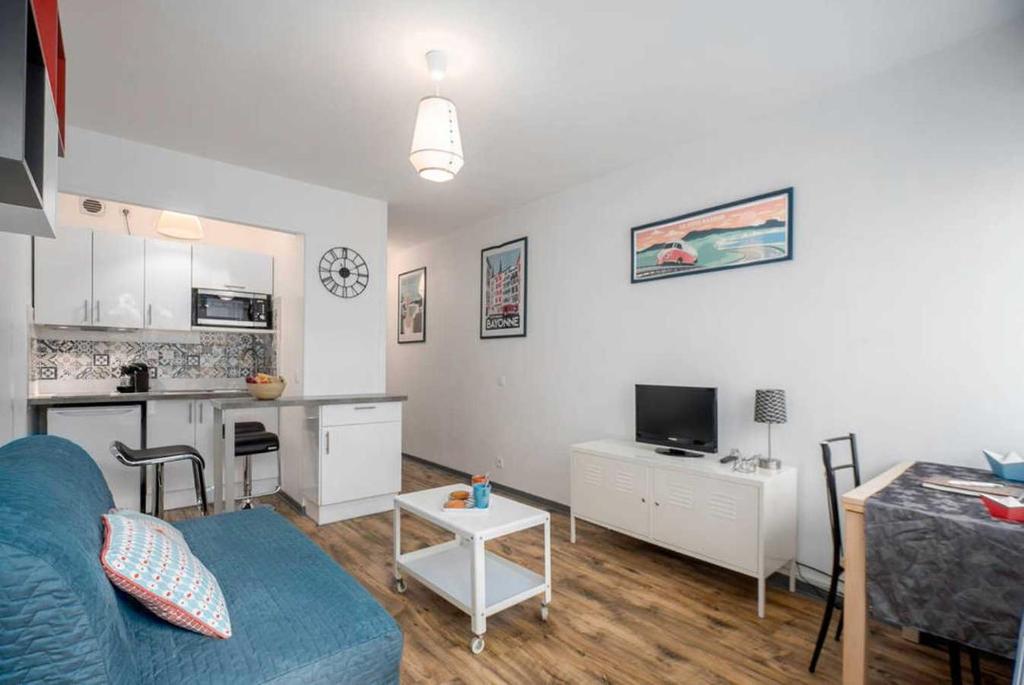 un salon avec un canapé bleu et une cuisine dans l'établissement Bayonne et Anglet à pied - Terrasse bois privative, à Anglet