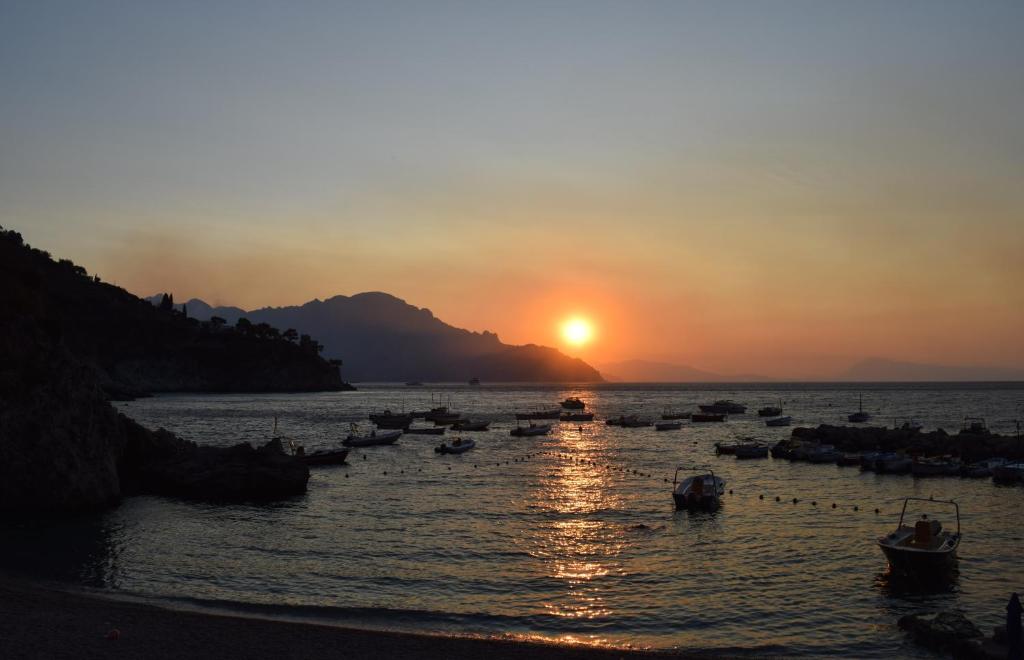 un grupo de barcos en el agua al atardecer en Casa della Marina - beach, seaview, wifi, en Conca dei Marini